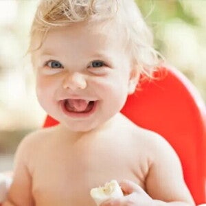 Nasmejan dojenček sedi na stolu.