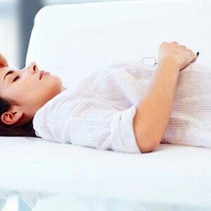 Ženska leži na postelji in razmišlja.