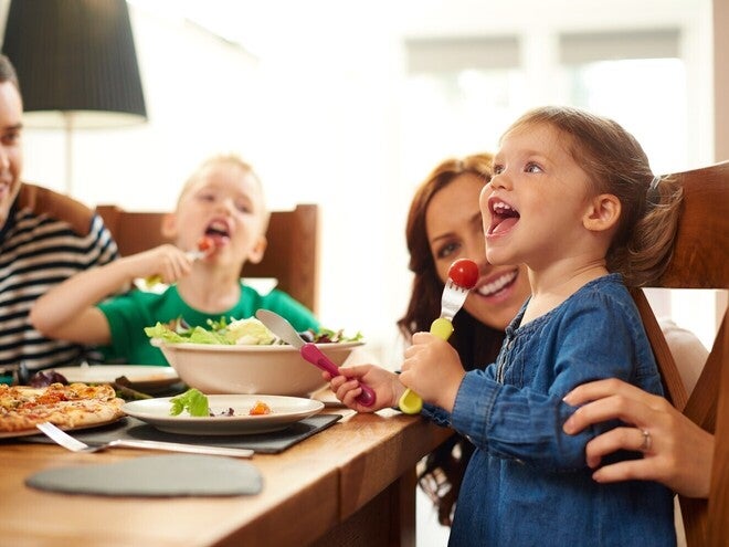 Družina sedi za mizo, kjer skupaj jé kosilo.