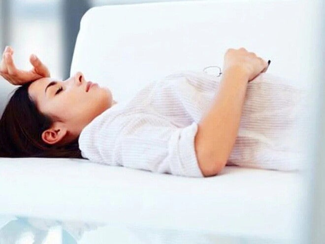 Ženska leži na postelji in razmišlja.